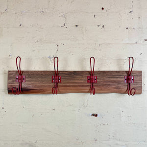 Upcycled brown wooden coat rack with red hooks. 