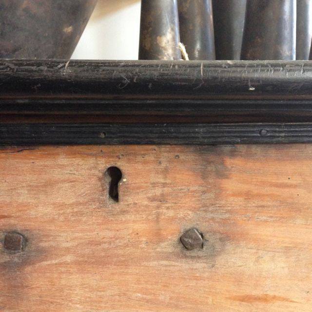 Close up of bottom corner, antique vintage storage and display cabinet, made from light and dark timber. 