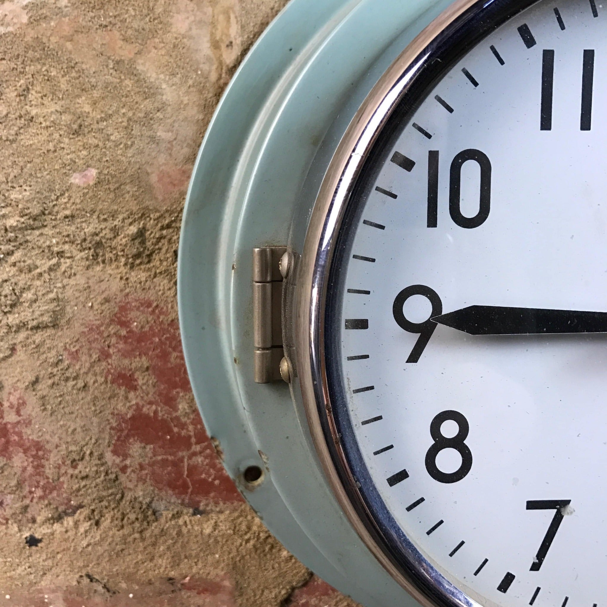 Close up of blue clock with metal frame and opening hinger. 