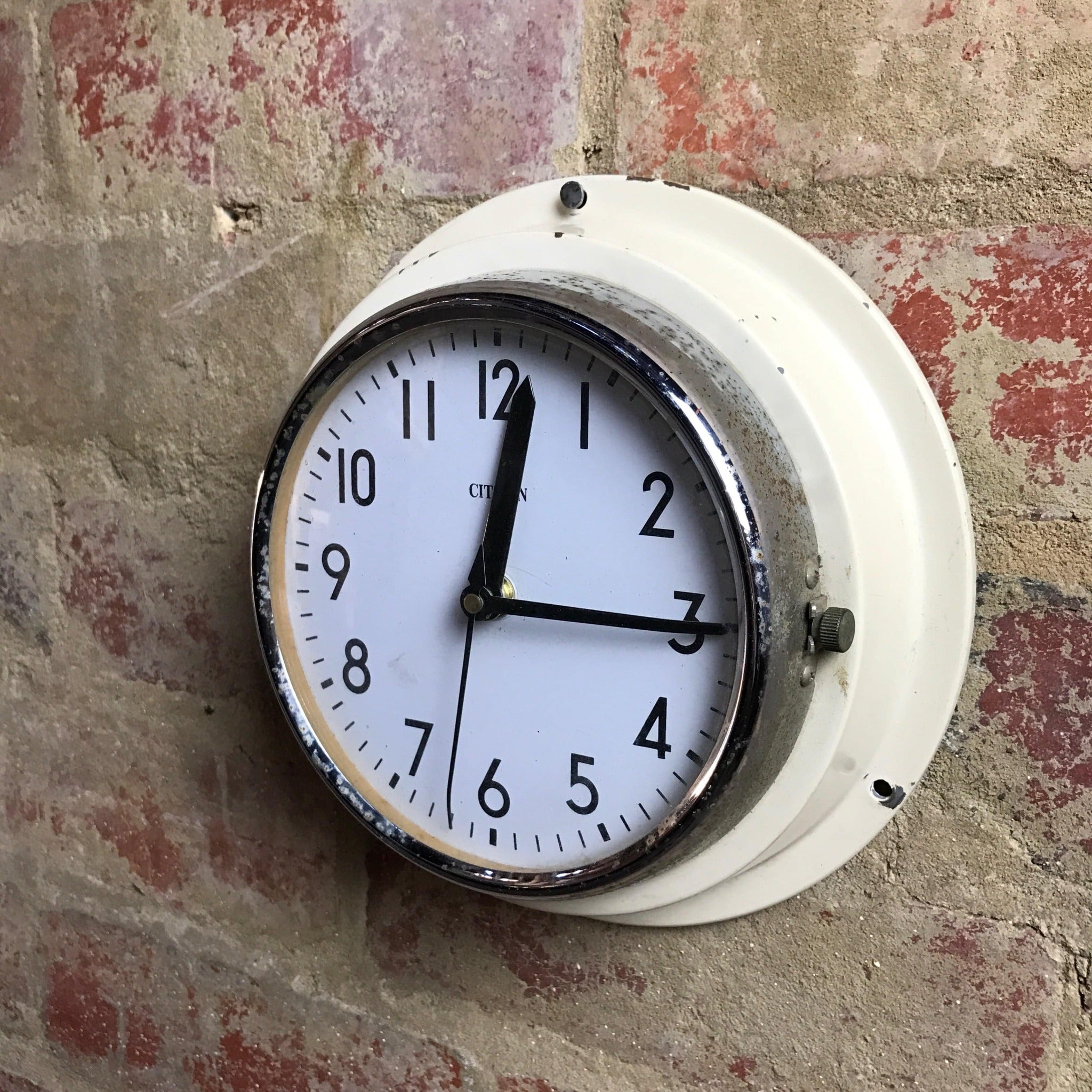 Rustic cream Citizen clock with thick metal frame. Red brick background. 