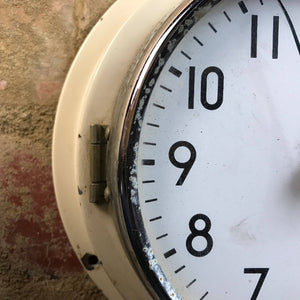 Close up of cream coloured vintage clock with metal frame around face. 