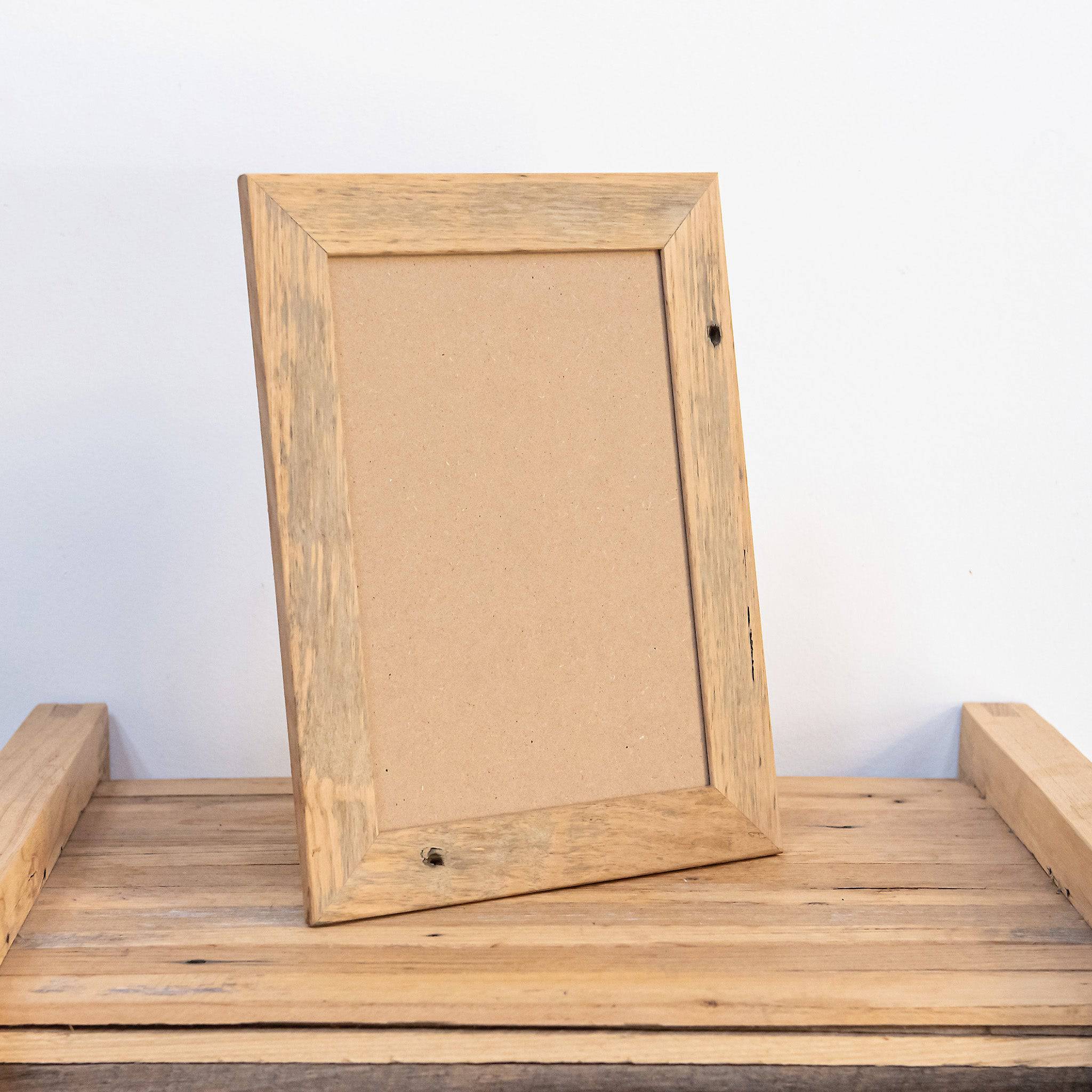 Free standing light wood wallnut colour picture frames on desk. 
