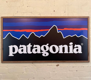 A SLIM NATURAL RECYCLED WOODEN PHOTO FRAME AROUND A PATAGONIA SIGN