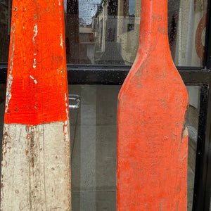 Close up of red, white and orange knife blade oar. Antique boat oars. 
